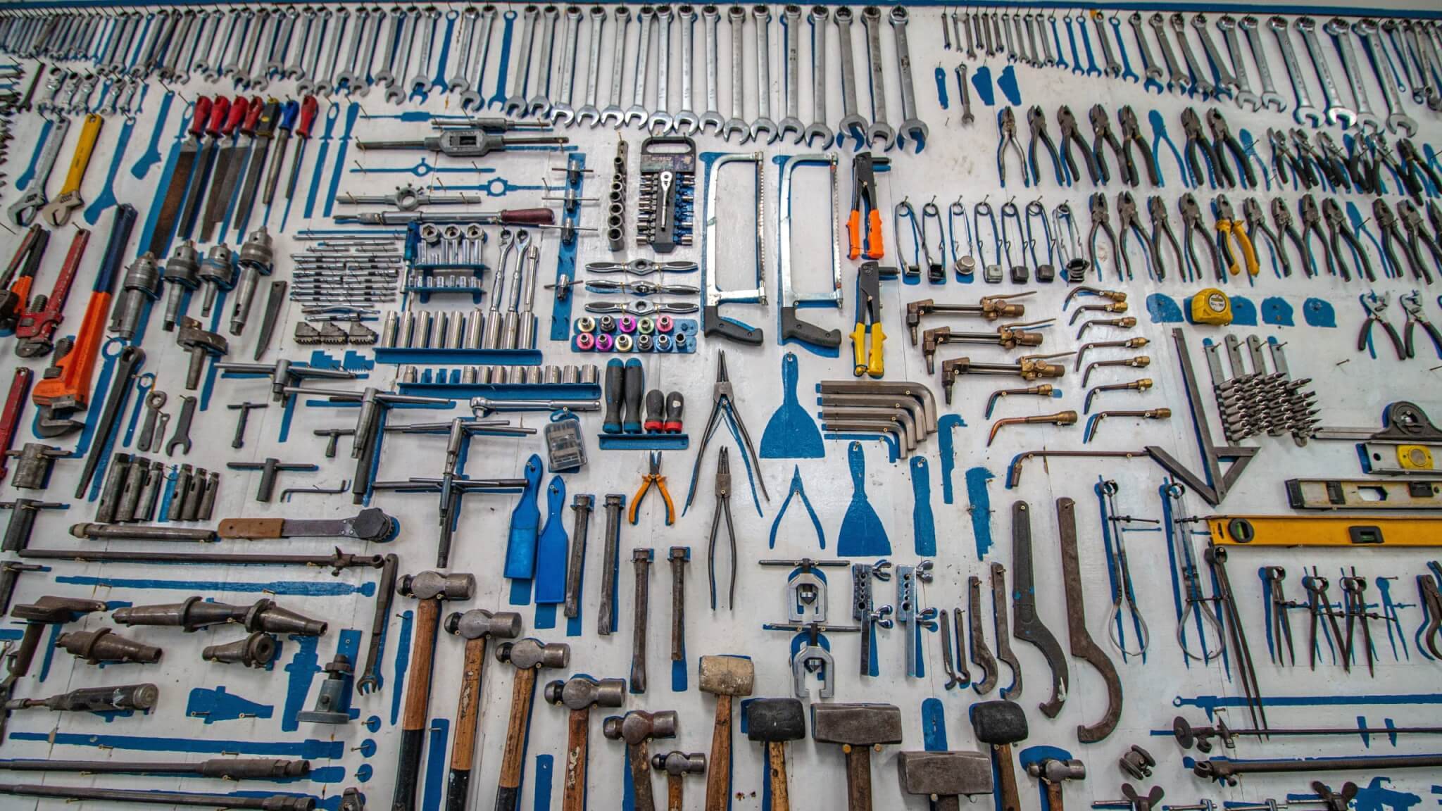 an absolute plethora of various tools in many shapes, sizes, and colors, primarily blue scraper tools but also a family of mallets and an array of wrenches never before seen by the humble eyes of man